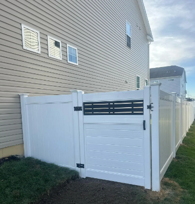 White vinyl side gate beside a tan house and fenced backyard.