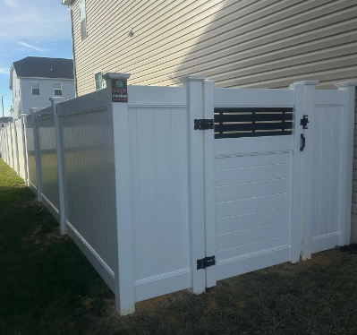 White vinyl privacy fence with a matching gate beside a beige house on a grassy yard