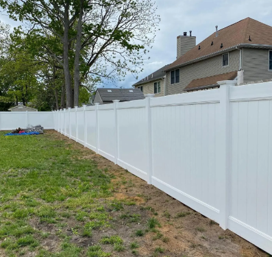 White vinyl fence along a grassy backyard beside a house and trees