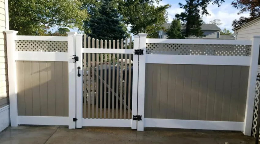 White-and-tan fenced driveway gate with a central black wrought-iron pedestrian gate