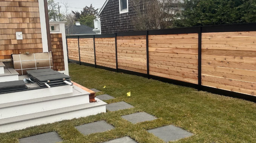 Backyard patio with white steps, gray stepping stones, grass, and a wooden privacy fence.