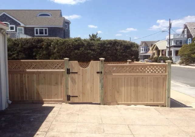 Wooden driveway gate with hedges, fronting a residential street and sidewalk