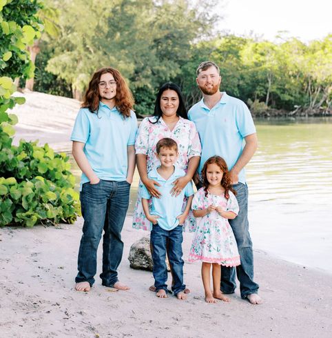 A family is posing for a picture in front of a wooden wall.
