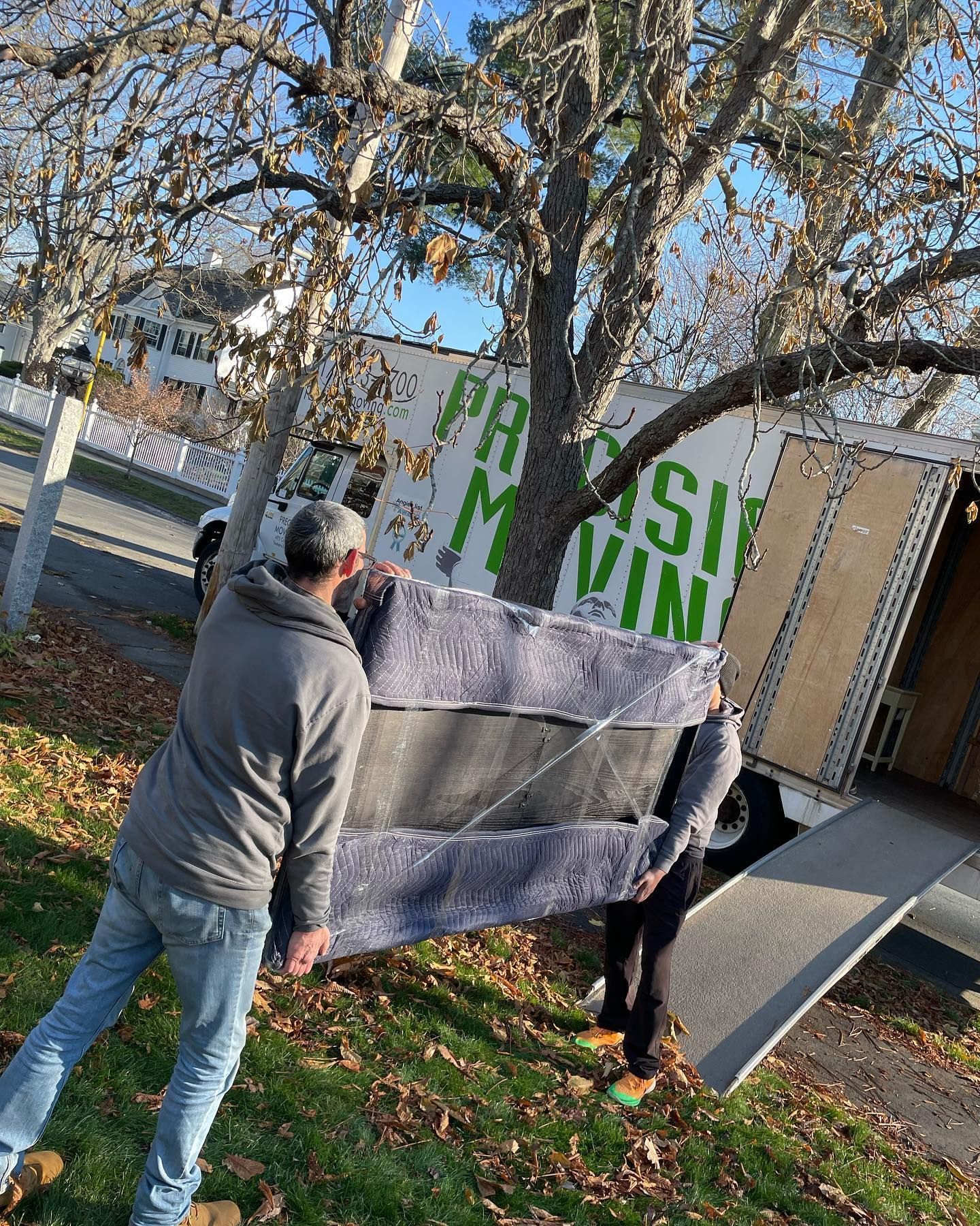 A man is carrying a couch in front of a moving truck.
