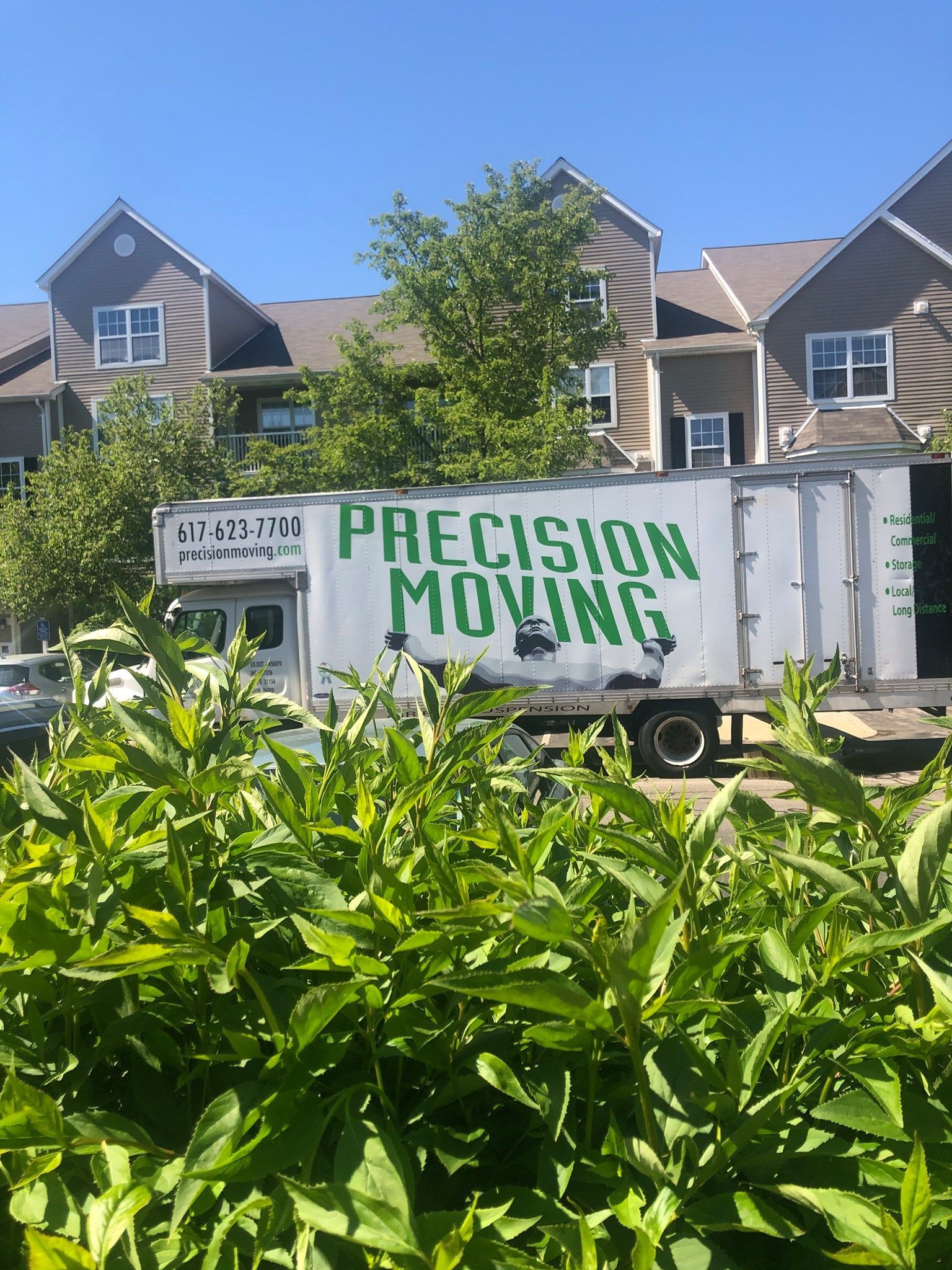 A precision moving truck is parked in front of a building.
