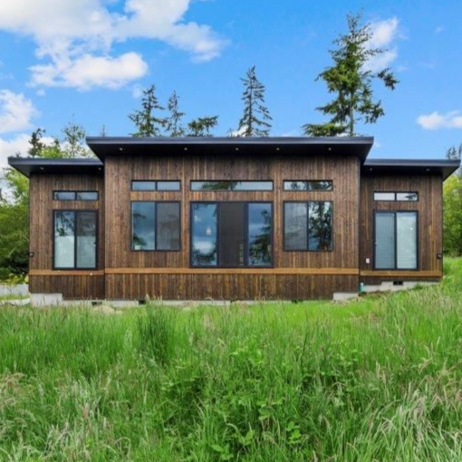 Modern tiny house with wood accents and carport, set against a desert sunset