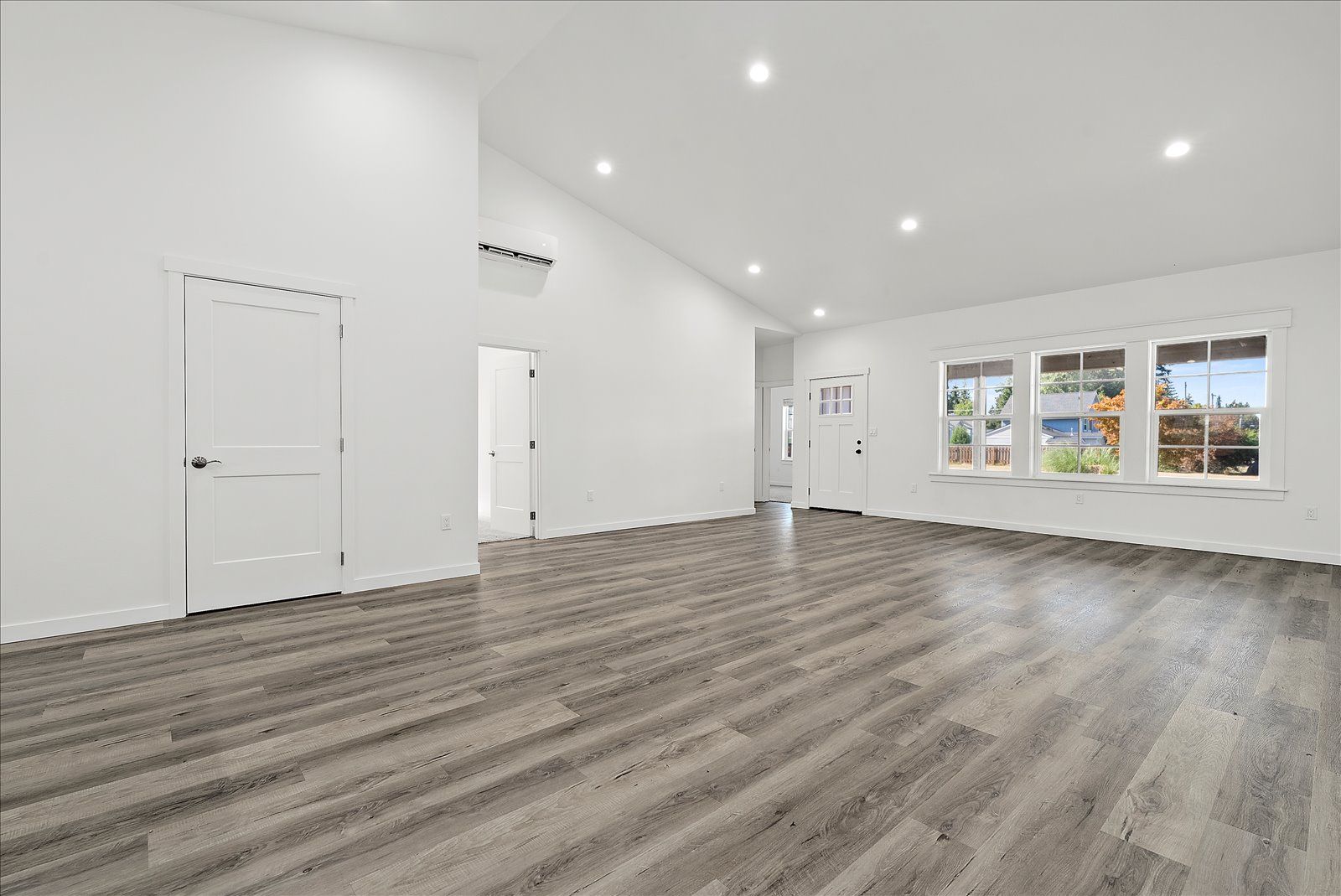 An empty living room with hardwood floors and white walls.