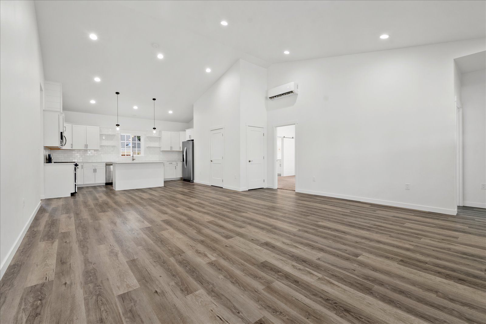 A large empty room with hardwood floors and white walls.