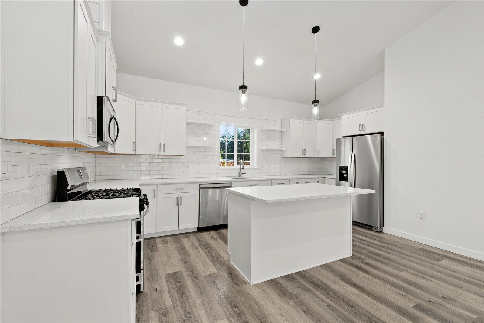 A kitchen with white cabinets , stainless steel appliances , and a large island.