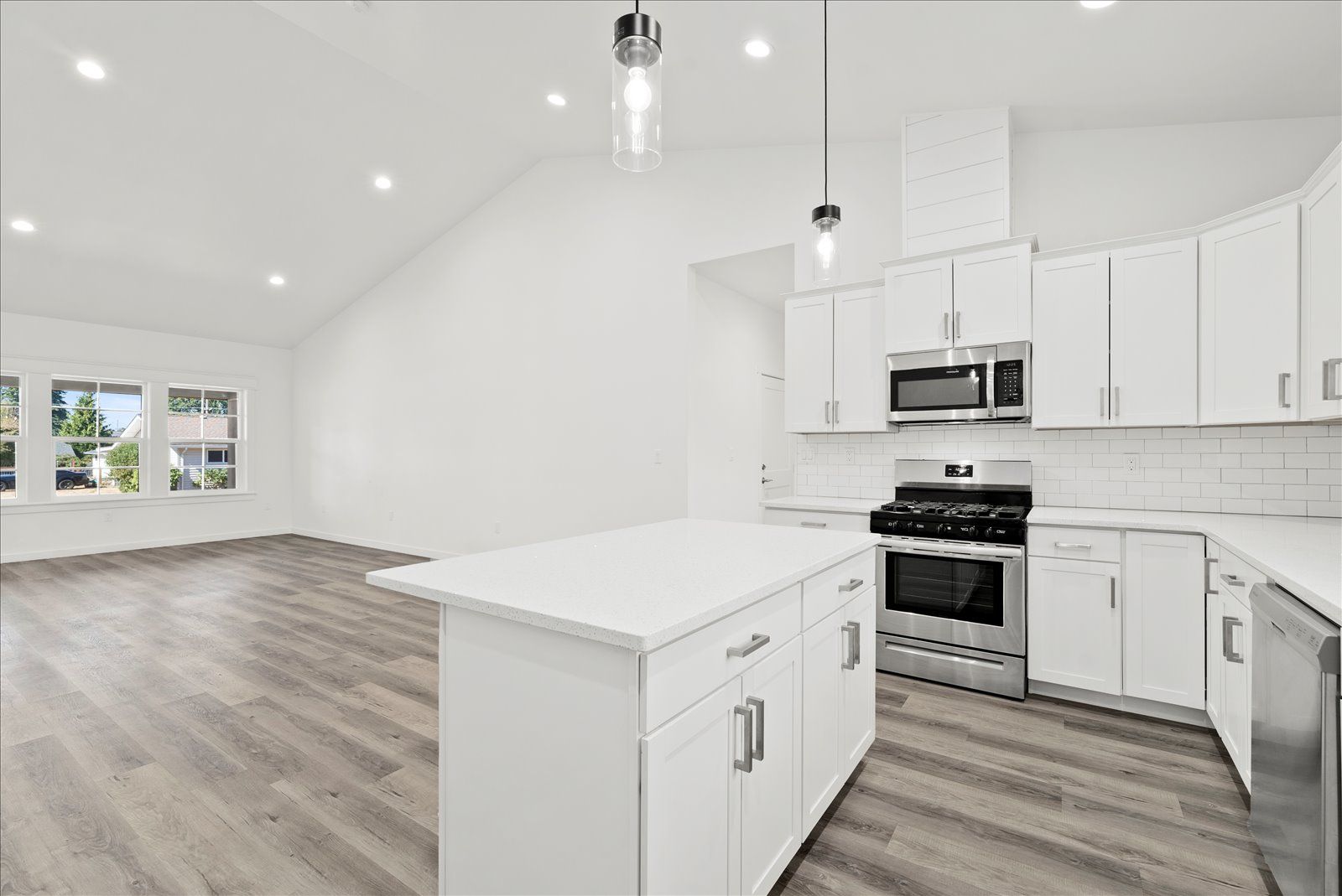 A kitchen with white cabinets , stainless steel appliances , and a large island.