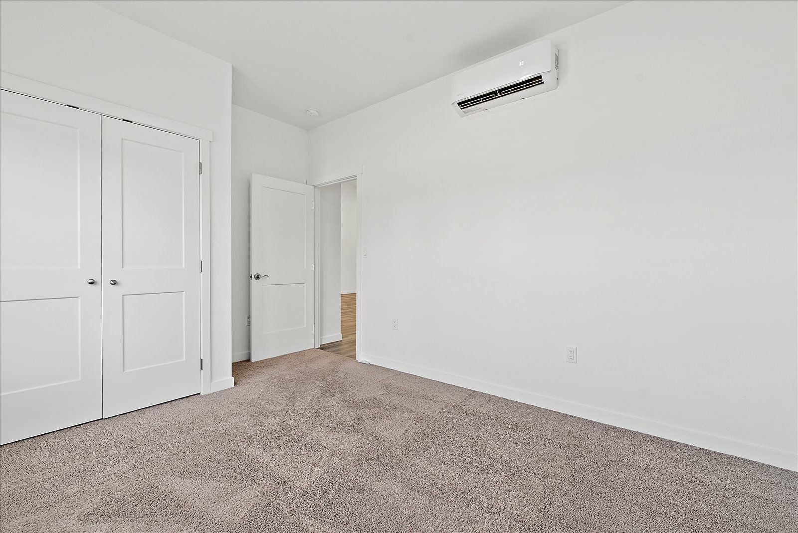 An empty bedroom with a carpeted floor and white walls.