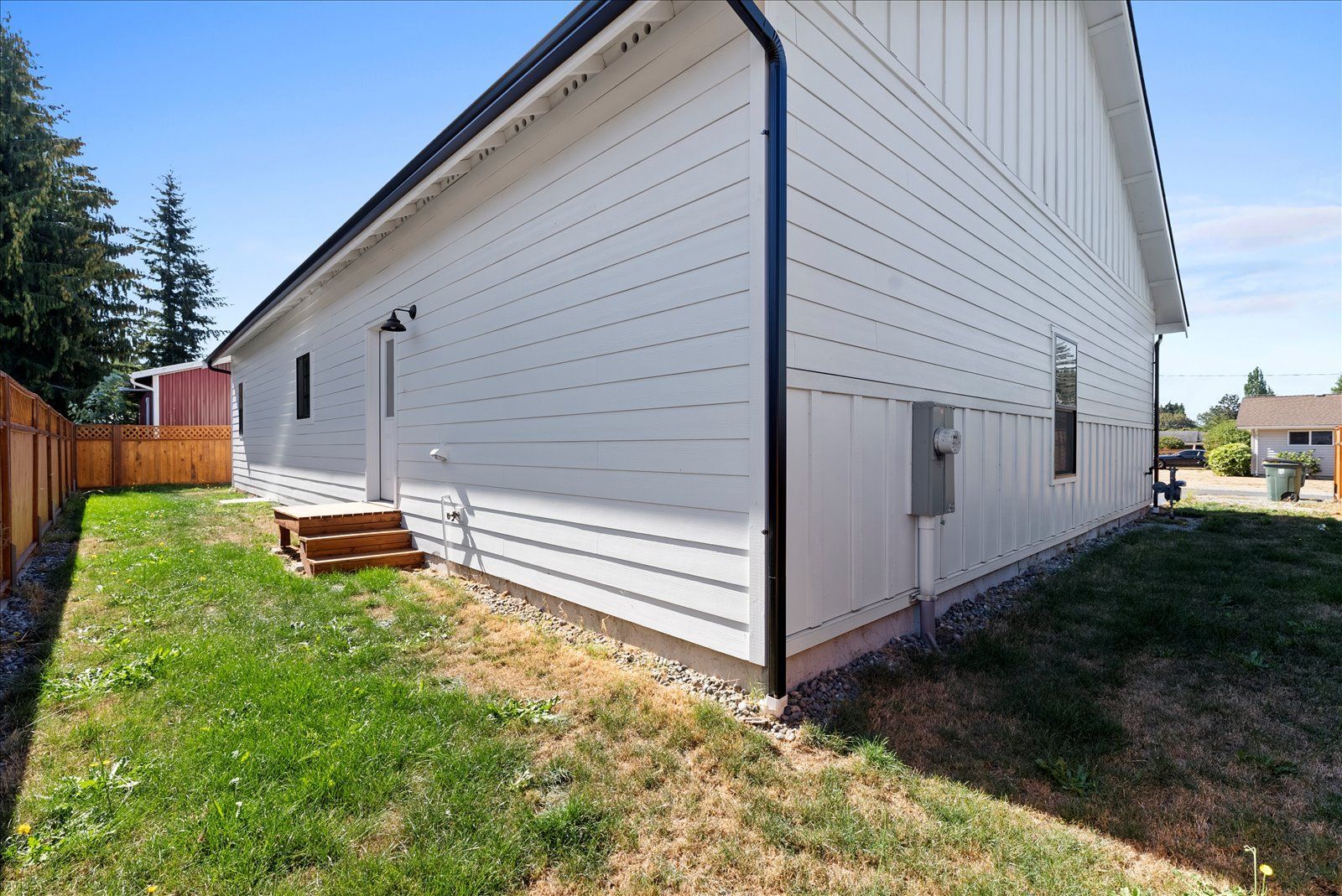 A white house with a black gutter and a picnic table in the backyard.