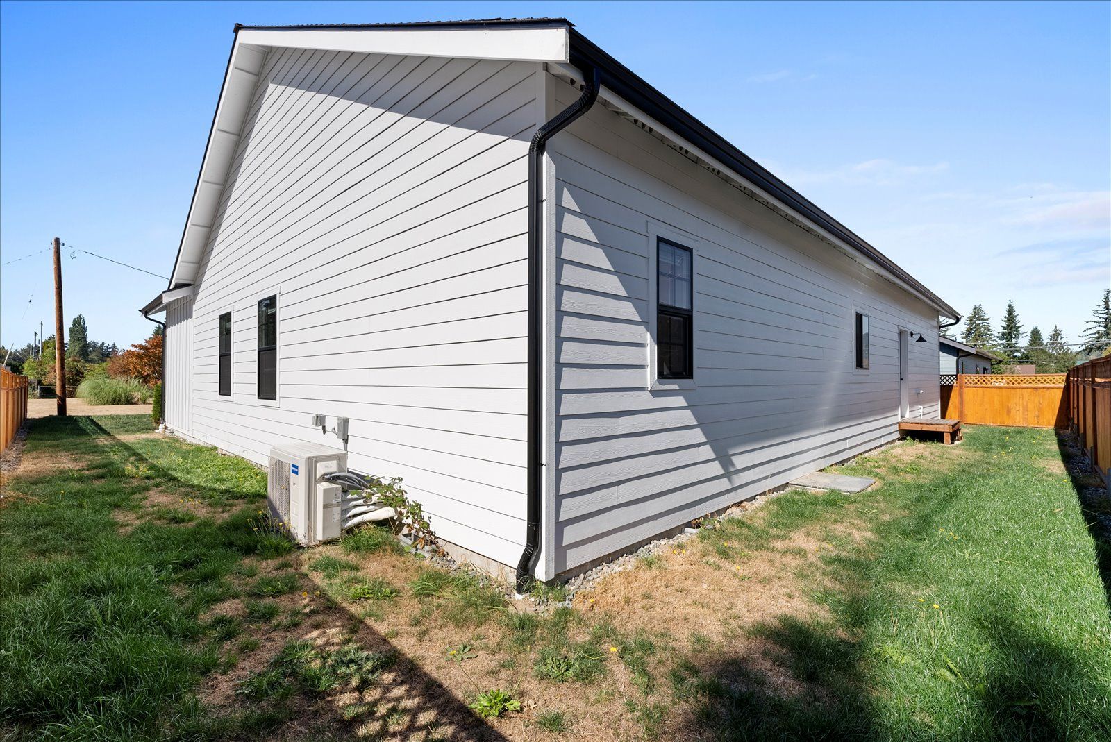 A white house with a lot of windows is sitting on top of a lush green field.