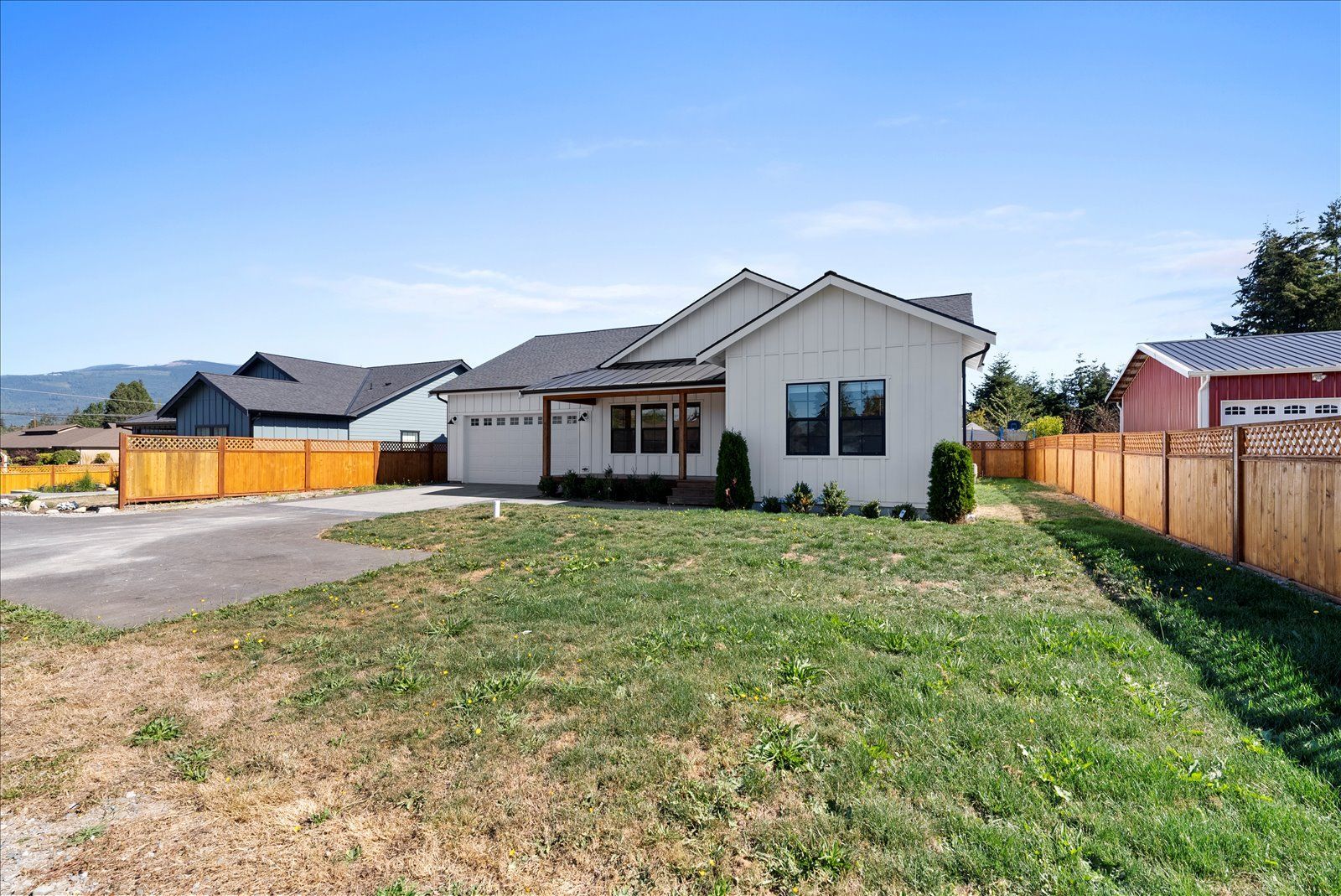 A white house with a large lawn in front of it and a wooden fence.