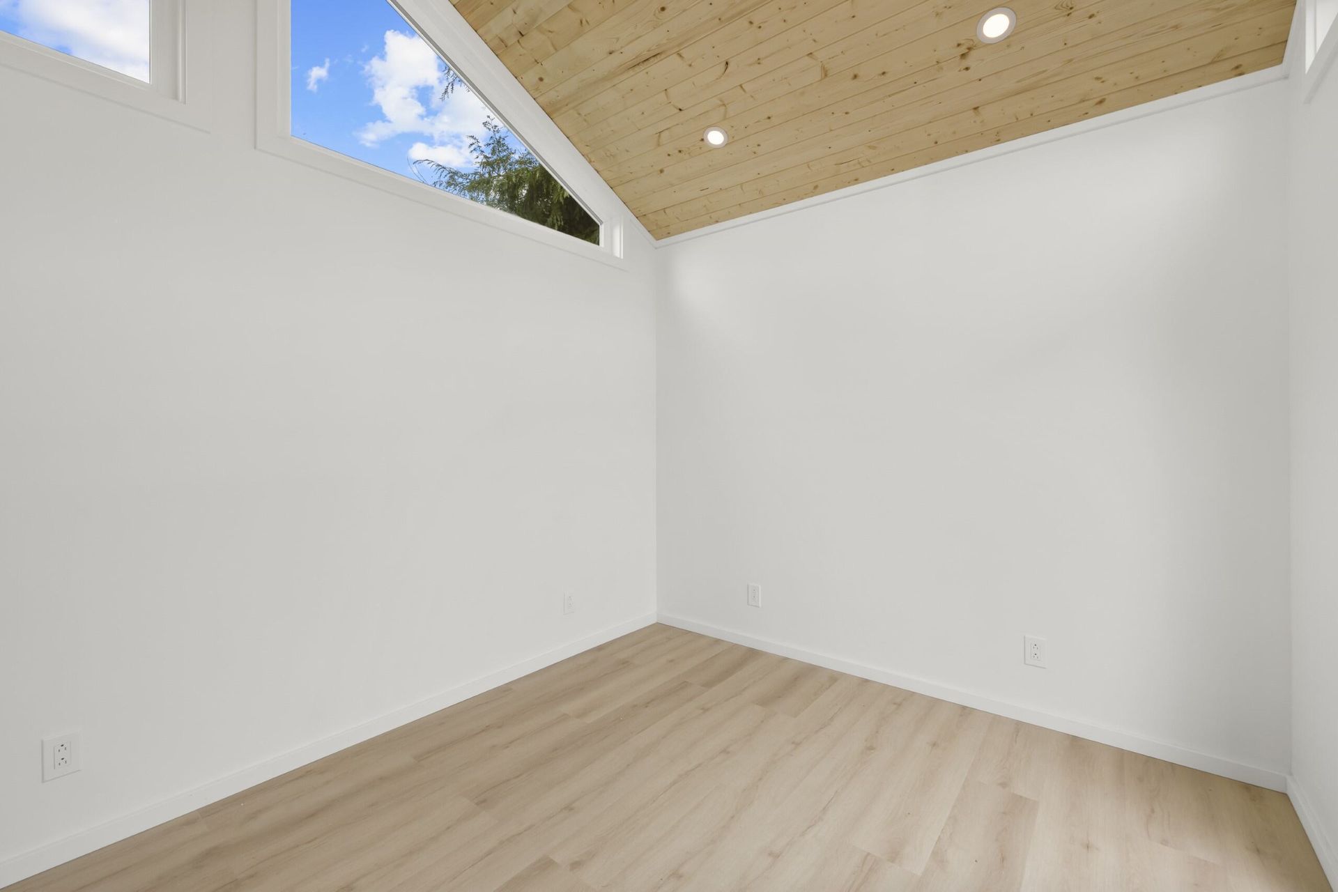 An empty room with a wooden ceiling and a window.