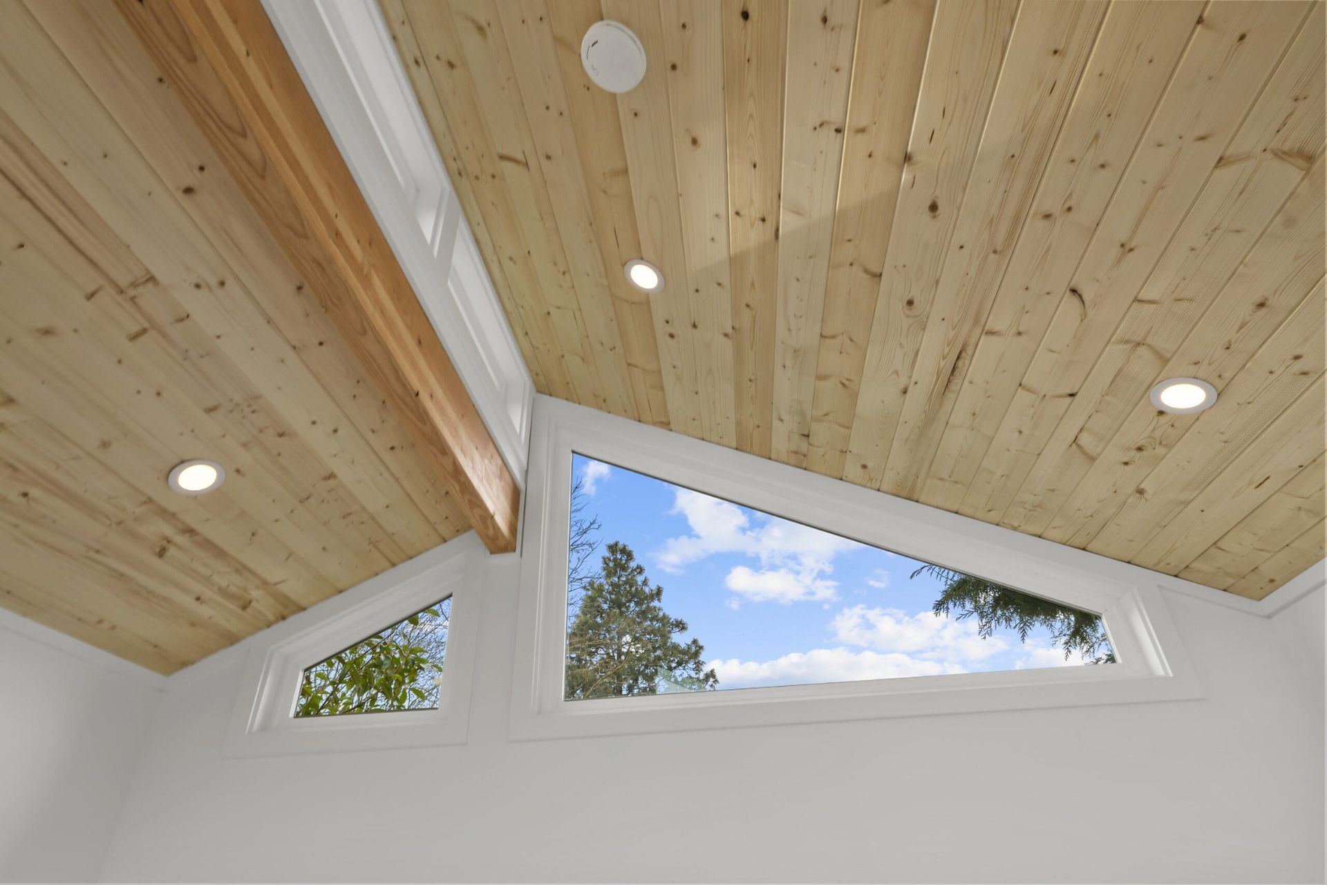 A room with a wooden ceiling and a window with a view of the sky.