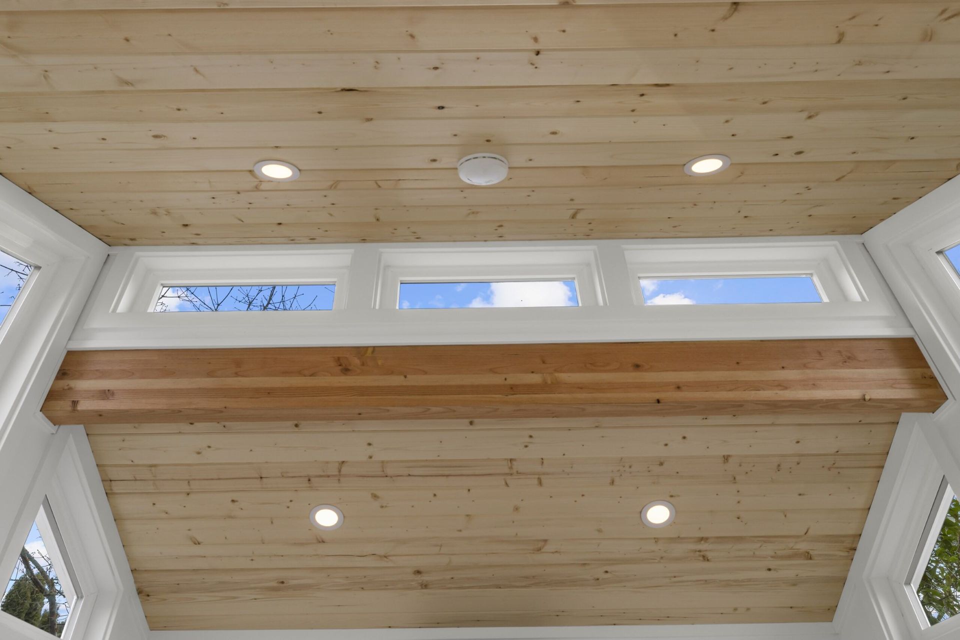 A wooden ceiling with three windows in a room.