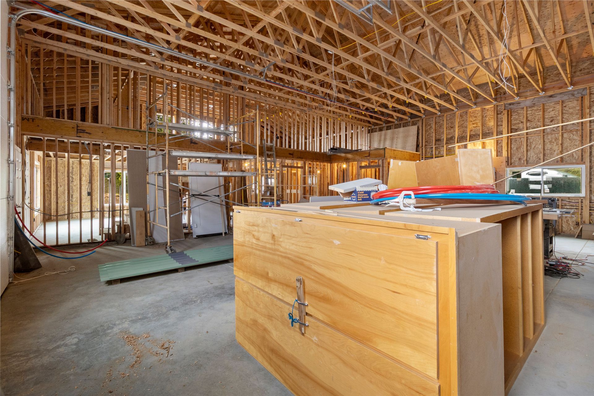 Interior view of a building under construction featuring exposed wood framing, roof trusses, and a large wooden structure.