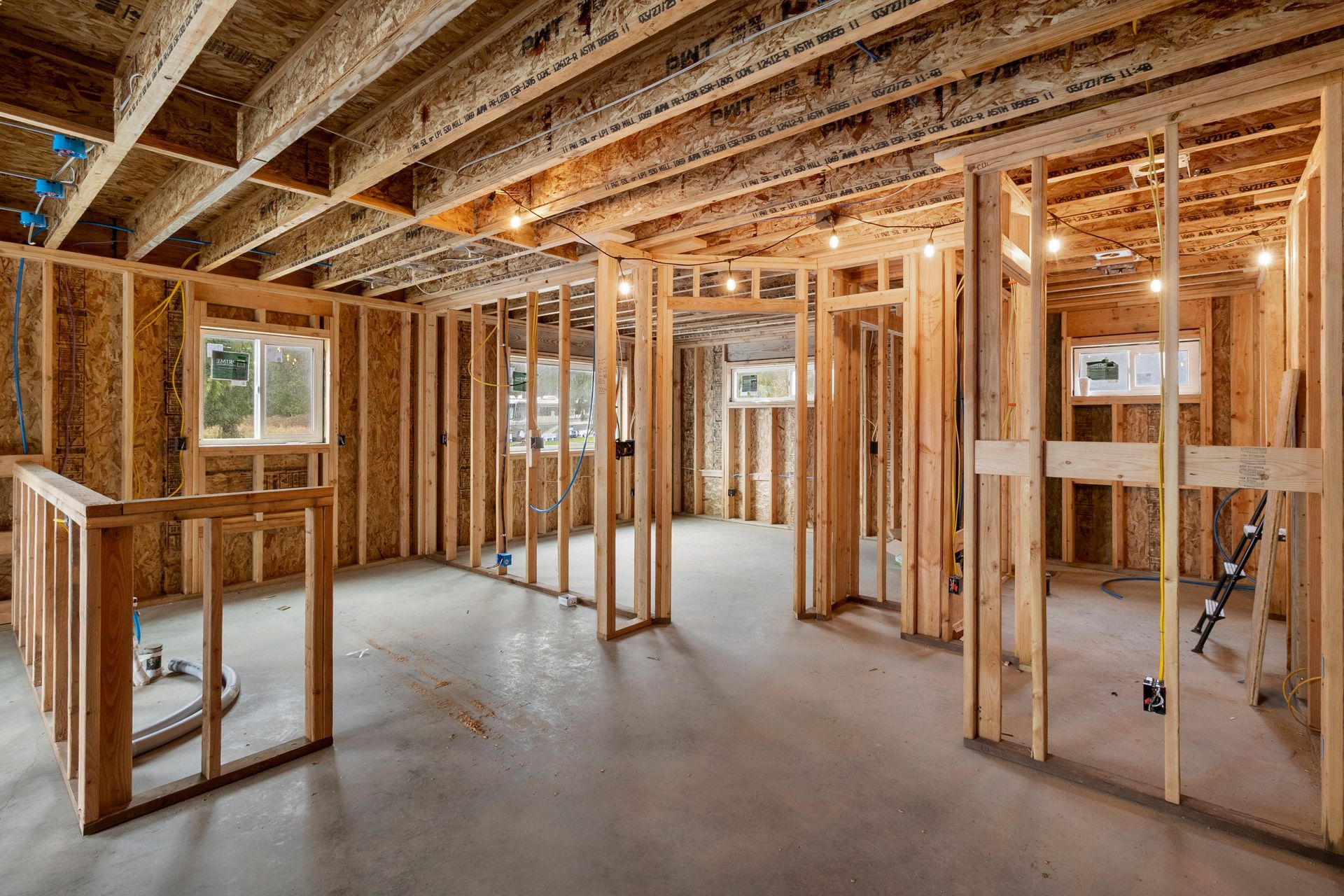 Interior view of a residential basement under construction, featuring wood framing, exposed ceiling joists, and concrete.