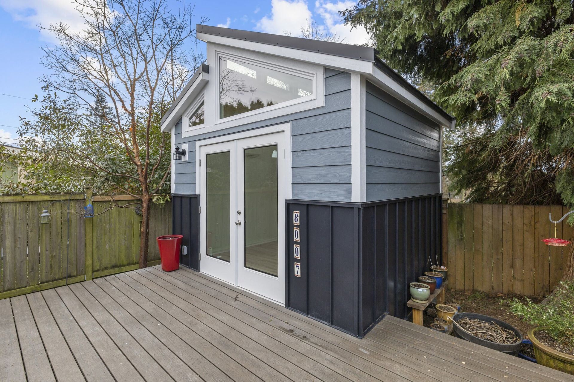 A small shed with a deck and a fence in the backyard.