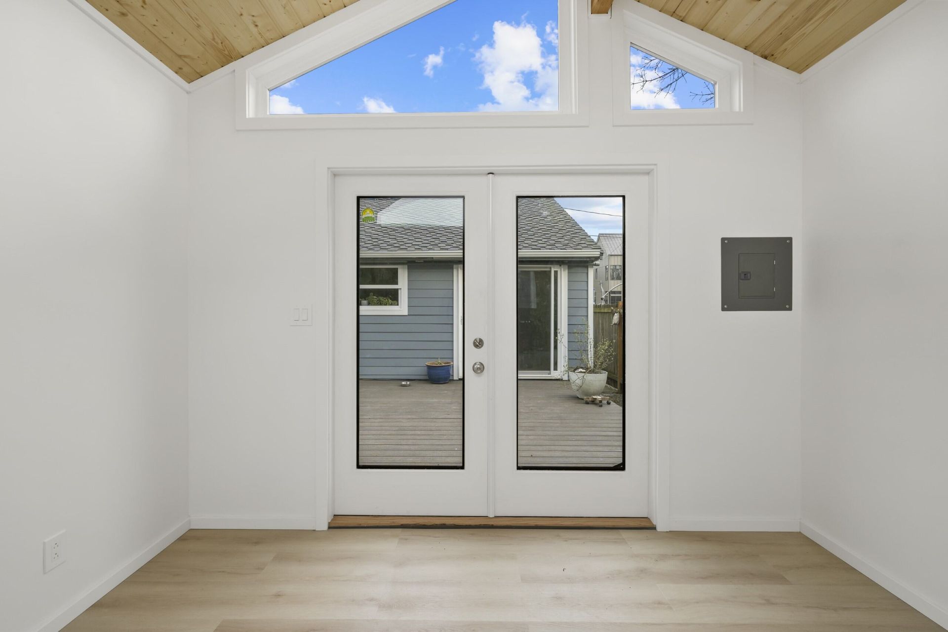 An empty room with a vaulted ceiling and a large window.