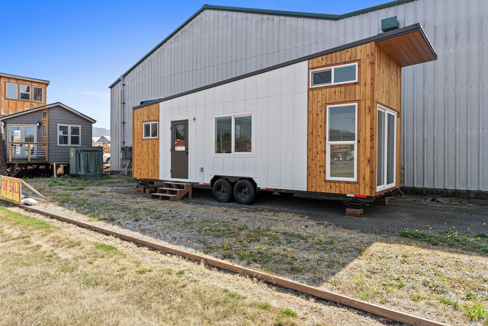 A tiny house on wheels is parked in front of a building.