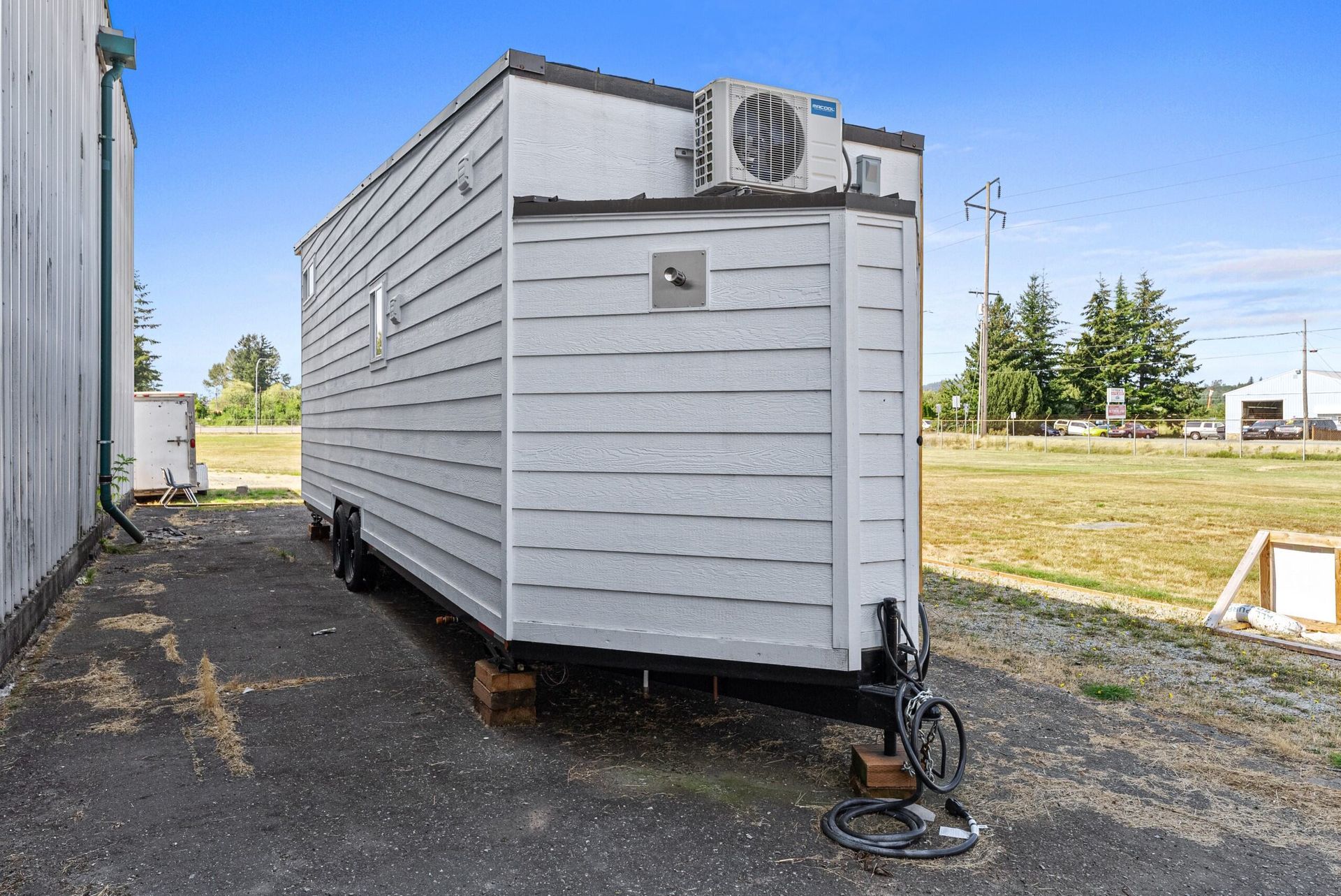 A small trailer is parked in a parking lot next to a building.