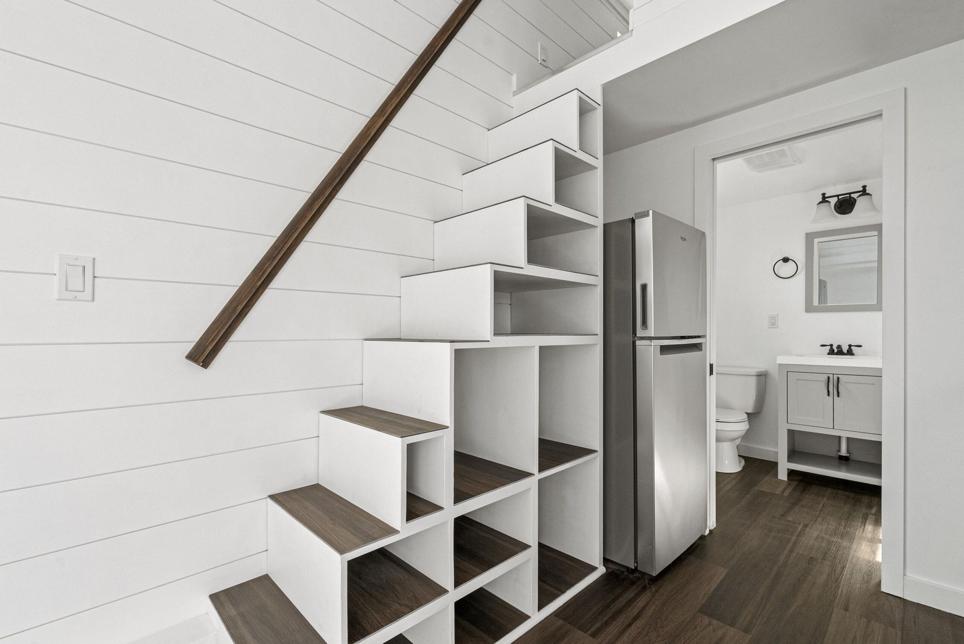 A staircase leading up to the second floor of a house next to a refrigerator.