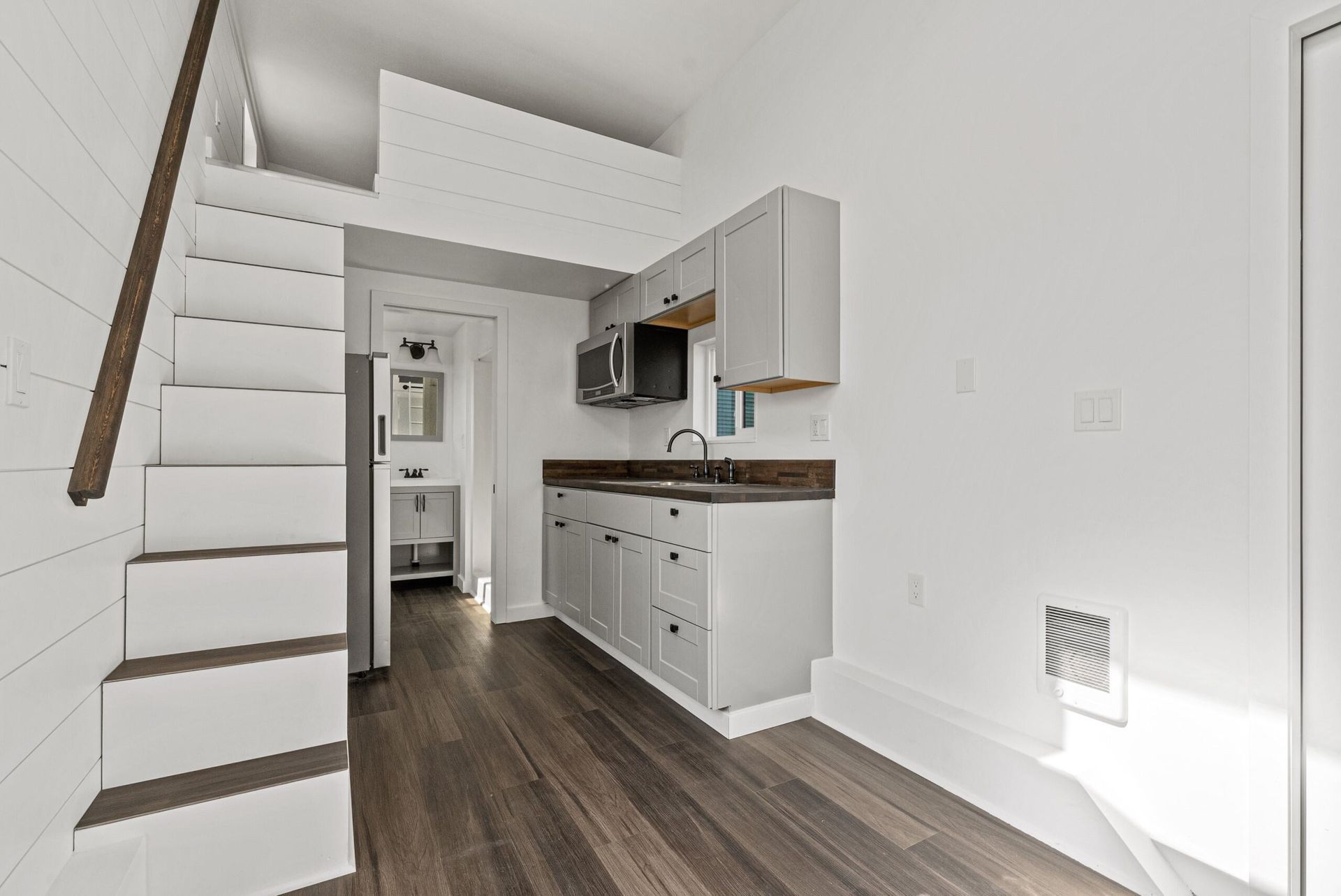 A small kitchen with stairs leading up to the second floor.