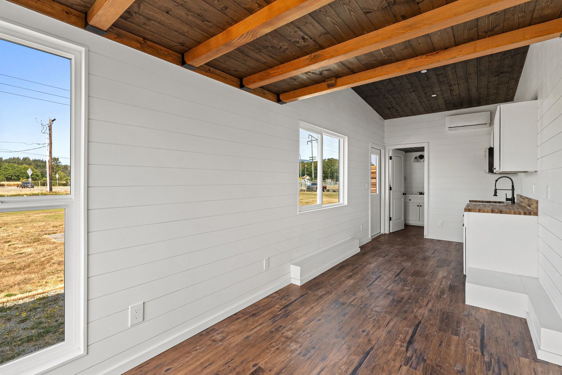 An empty room with hardwood floors , white walls and a wooden ceiling.