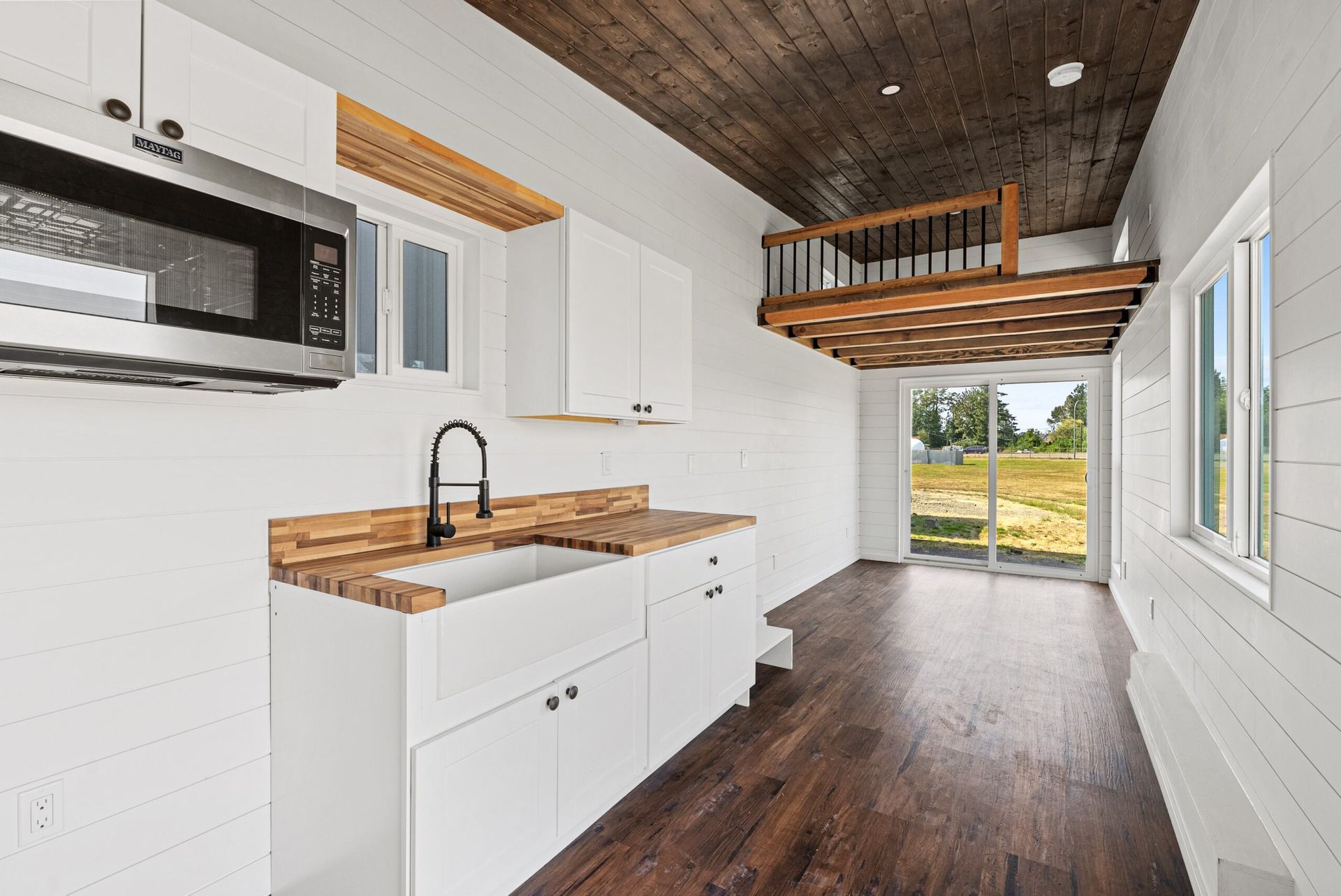 A kitchen with a sink, microwave, and bunk bed.