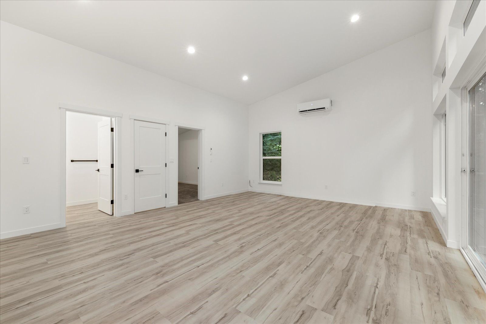 An empty living room with hardwood floors and white walls.