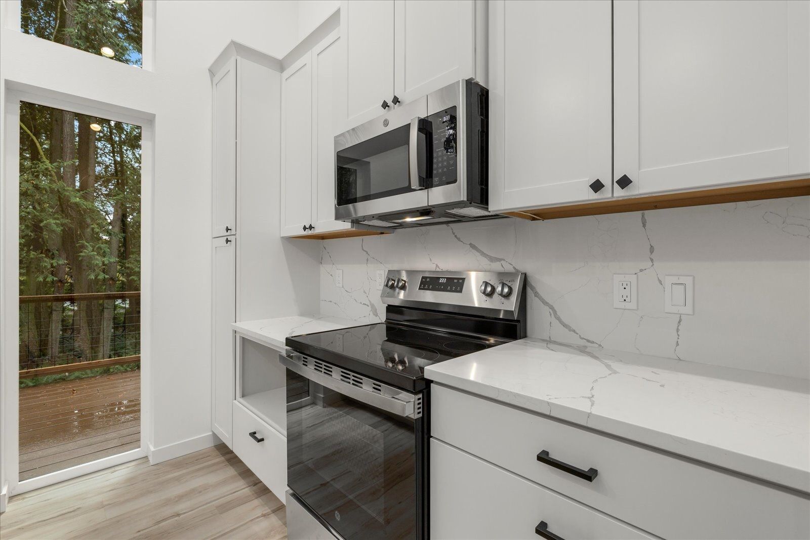 A kitchen with white cabinets, stainless steel appliances, a stove and a microwave.