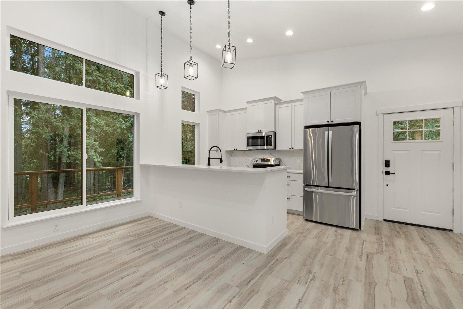 An empty kitchen with stainless steel appliances and a large island.