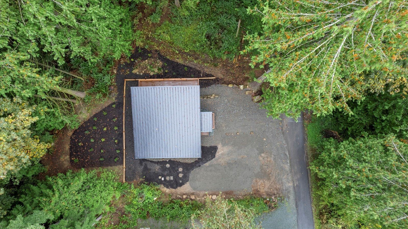 An aerial view of a small house in the middle of a forest.
