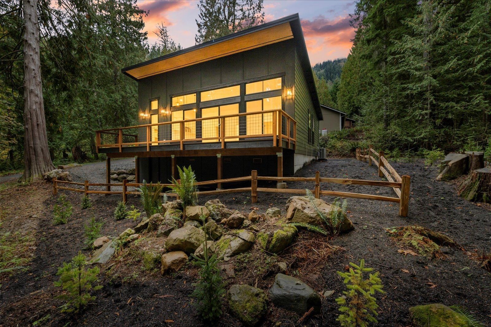 A small house with a deck in the middle of a forest.