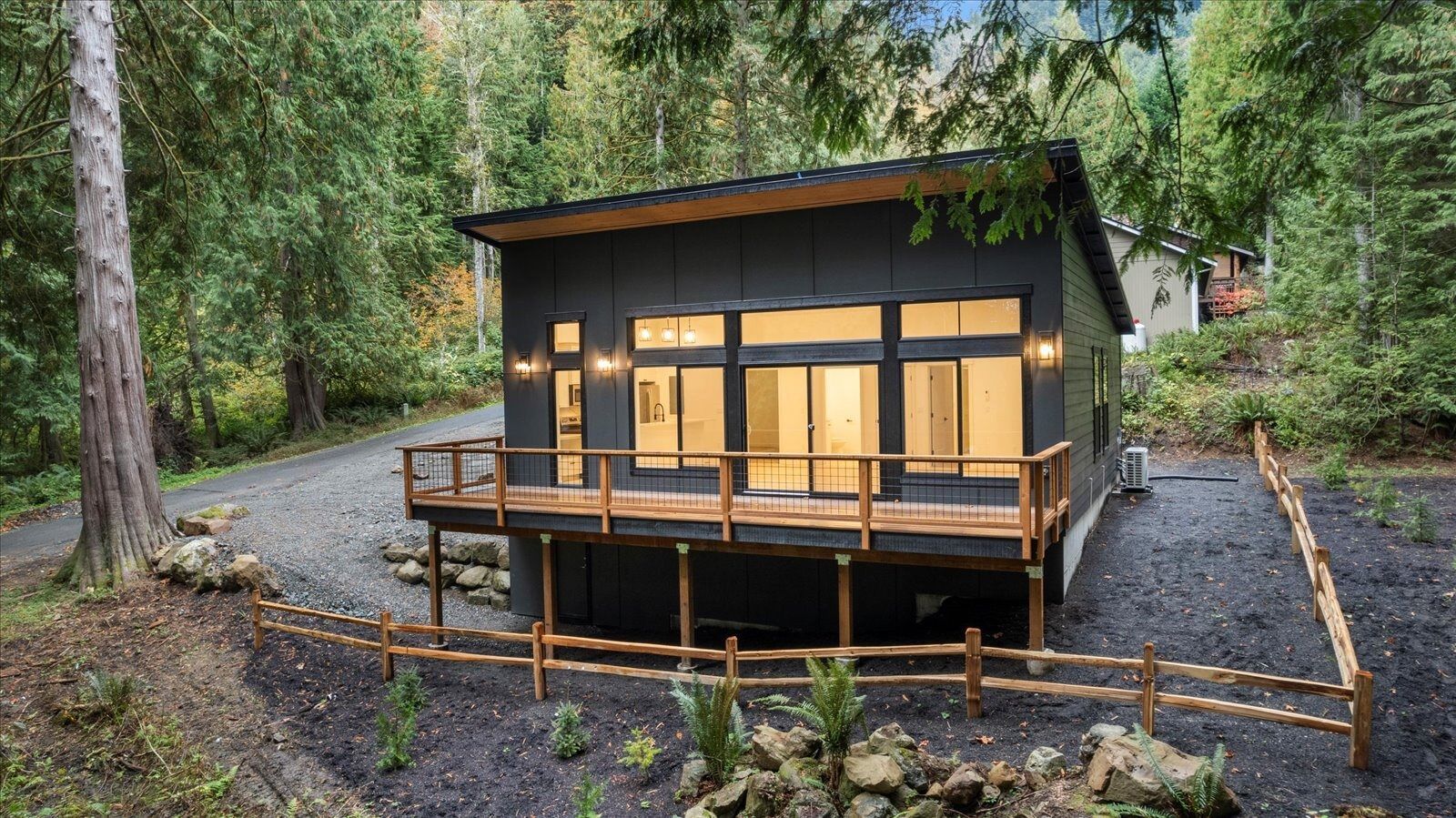 A small house with a deck in the middle of a forest.