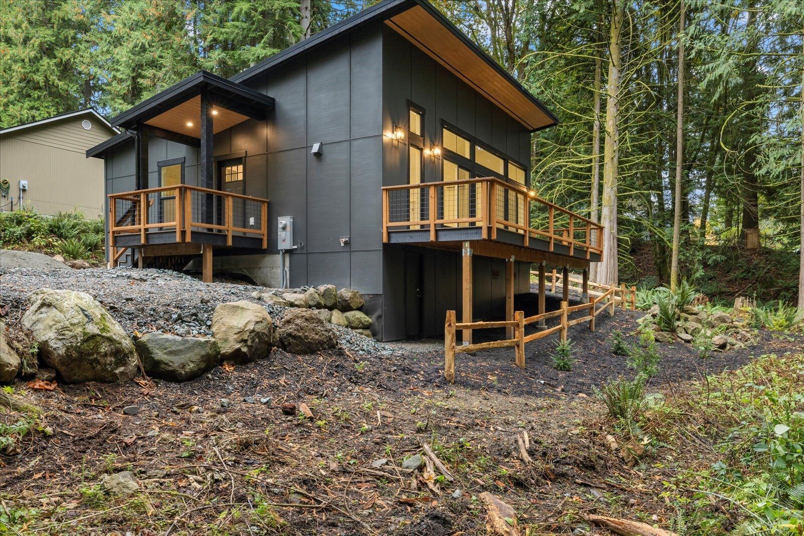 A small house with a deck in the middle of a forest.