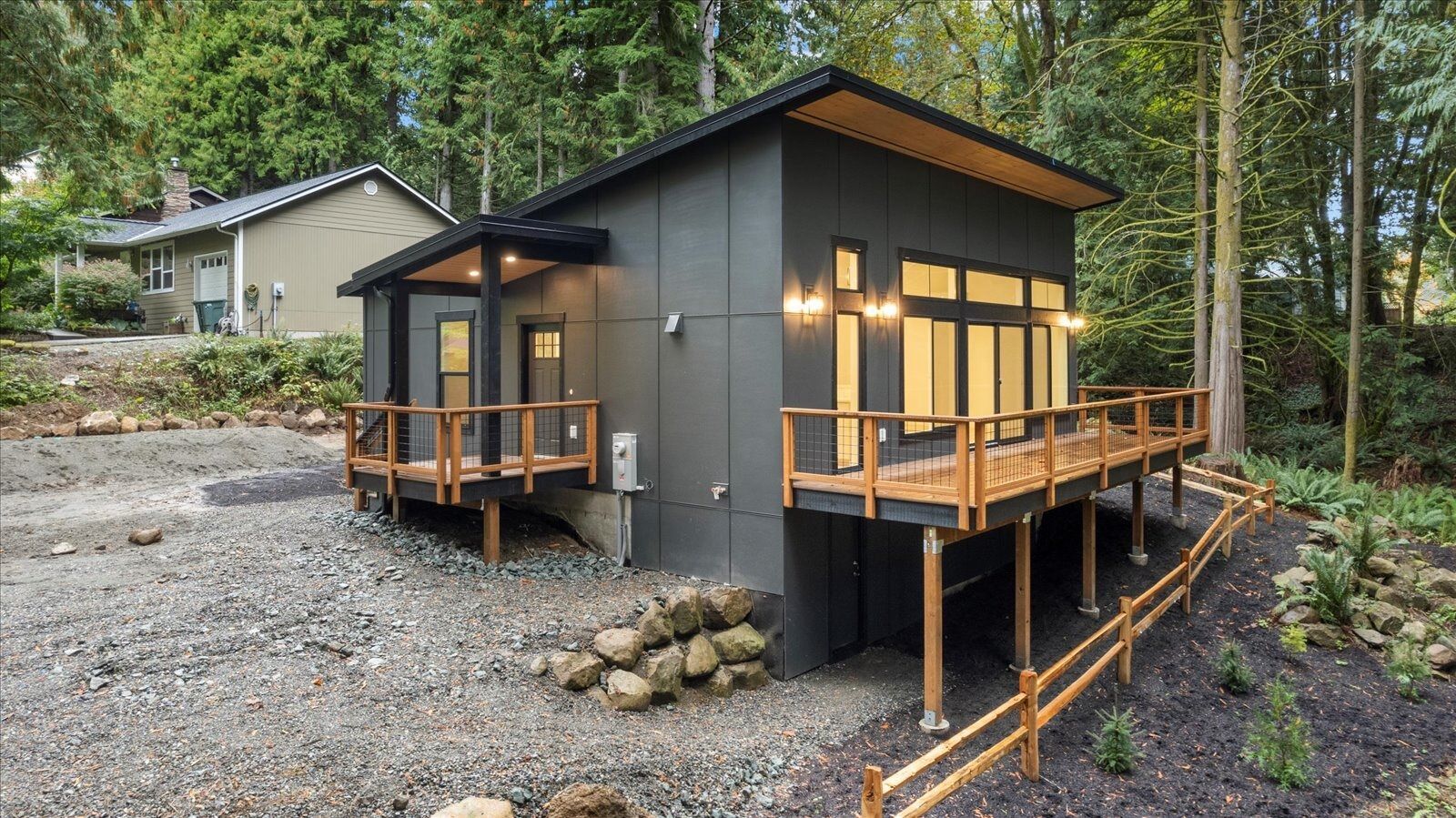 A small house with a wooden deck in the middle of a forest.