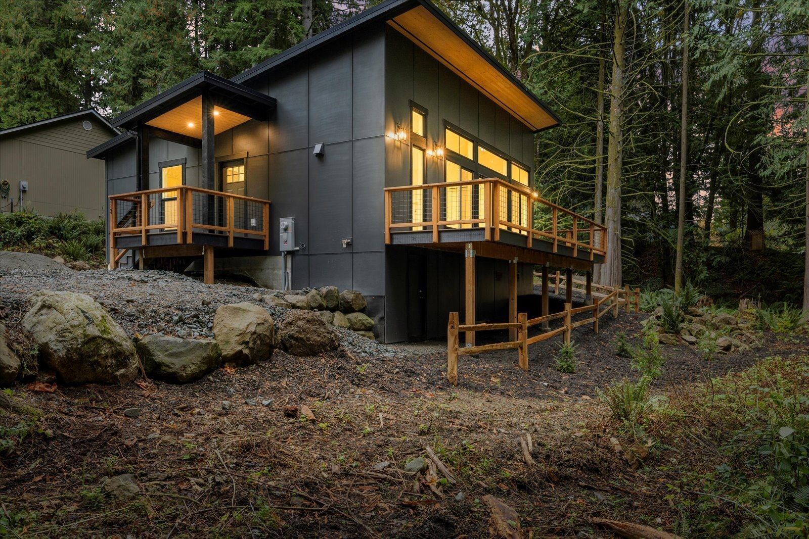 A small house with a deck in the middle of a forest.