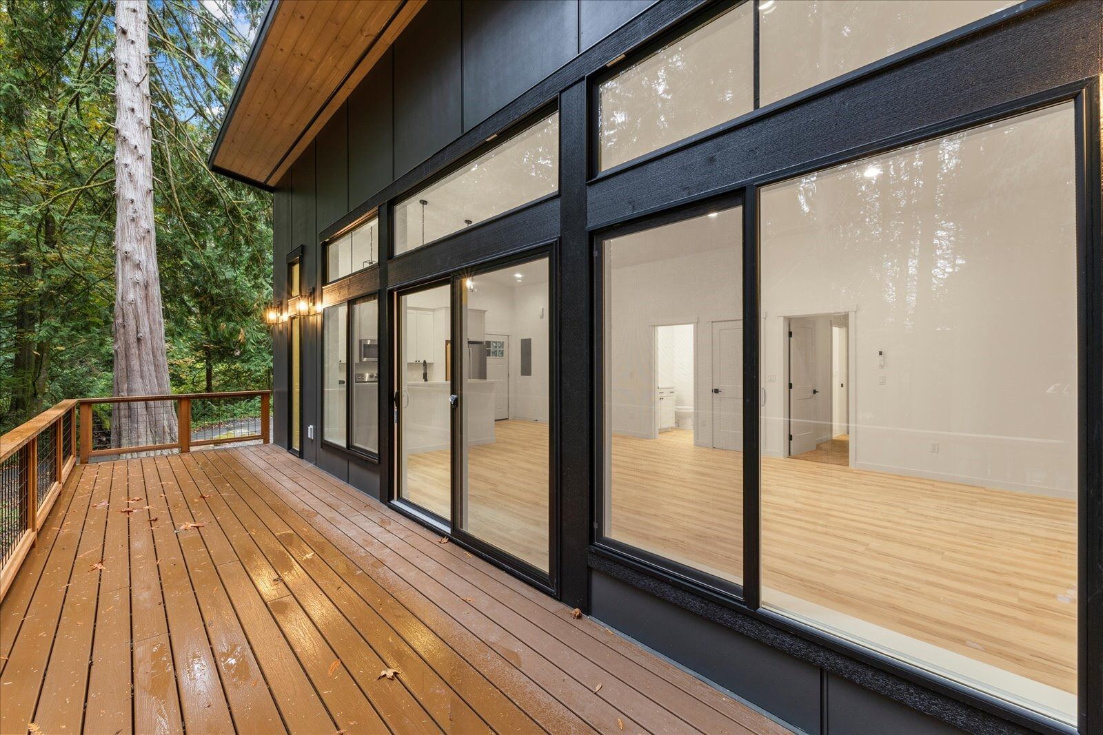 A modern house with a large deck and lots of windows.