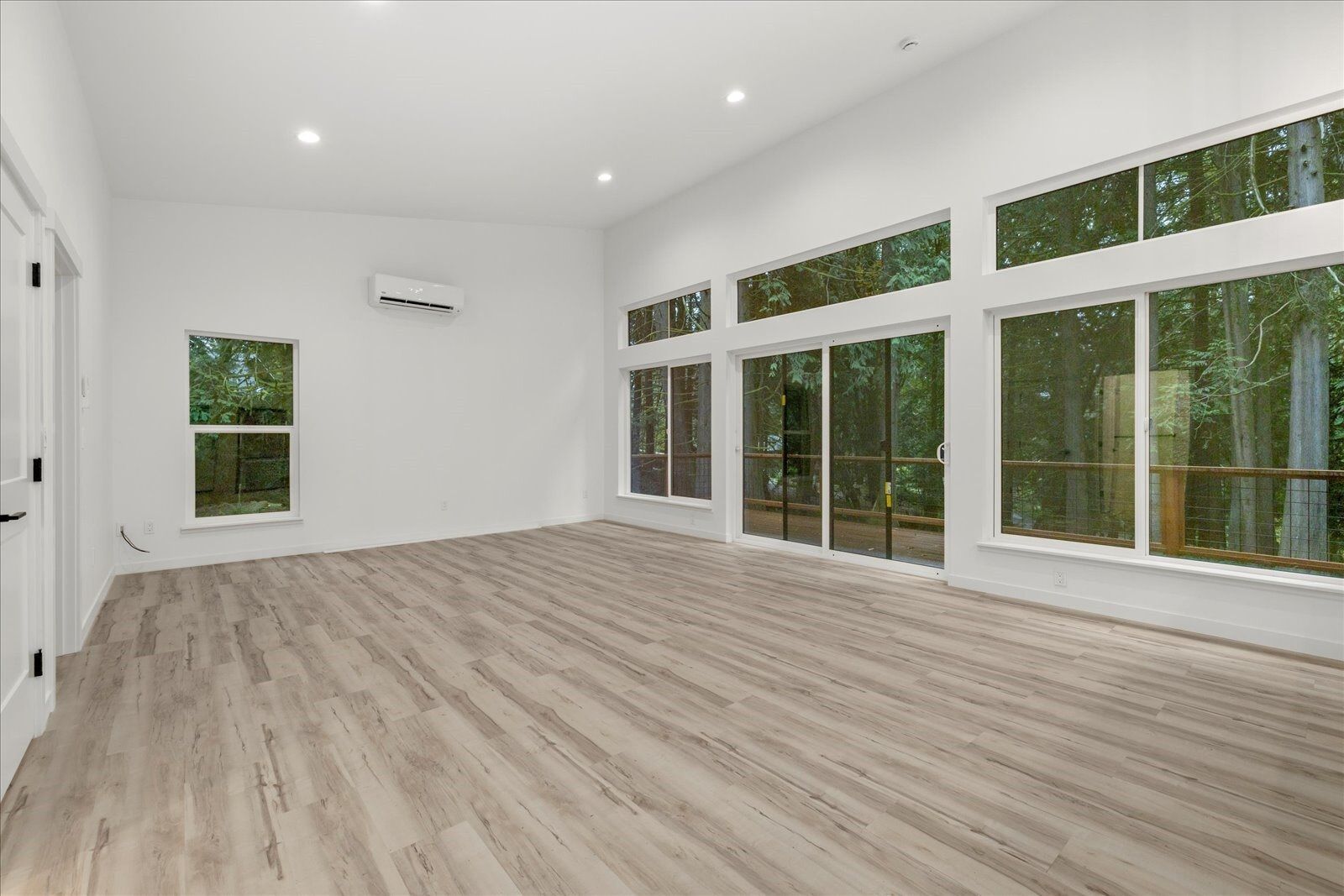 An empty living room with hardwood floors and lots of windows.
