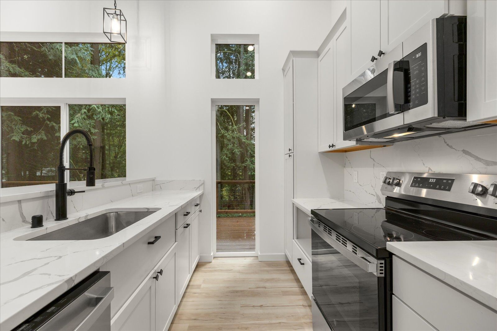 A kitchen with white cabinets, stainless steel appliances, a sink and a microwave.
