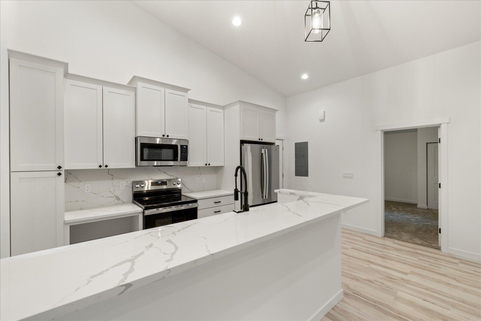 A kitchen with white cabinets, stainless steel appliances, and a large island.