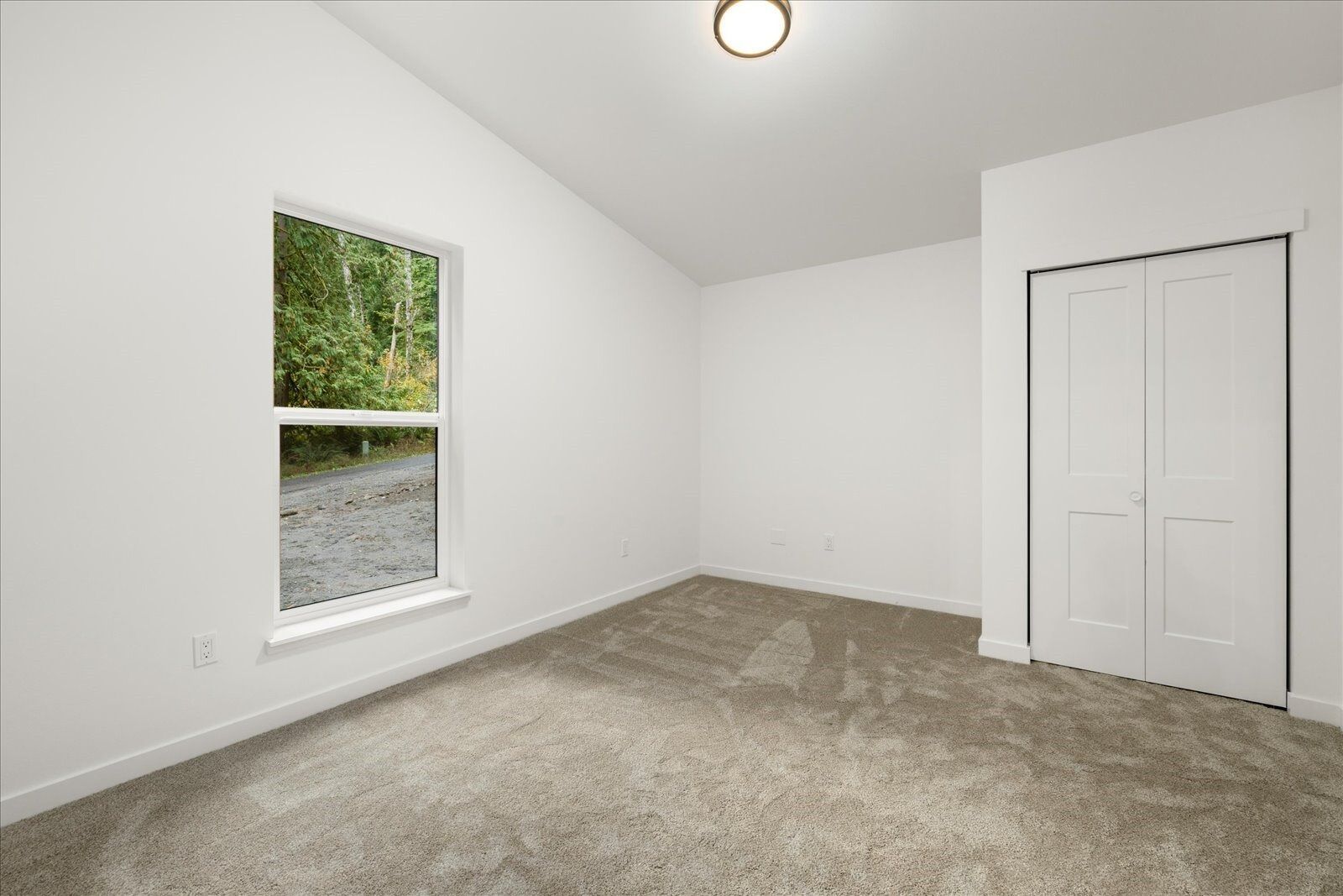 An empty bedroom with a window and a closet.