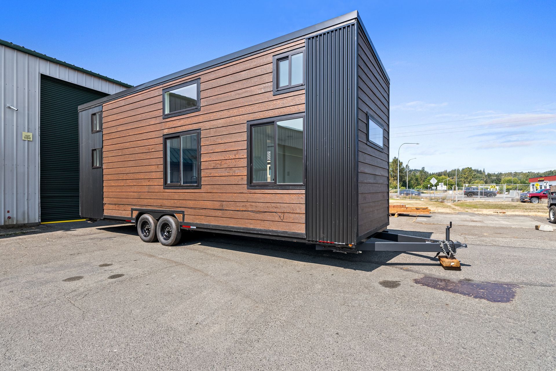 A tiny house is parked in a parking lot next to a building.