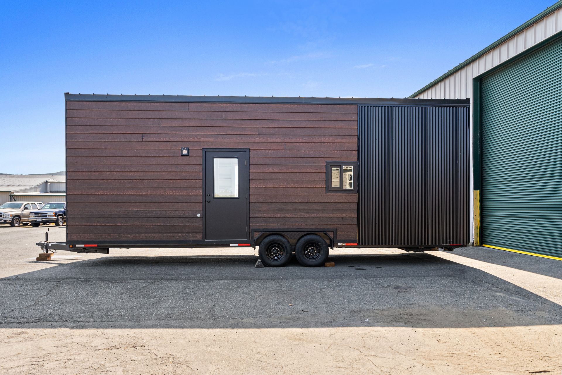 A tiny house on wheels is parked in front of a building.