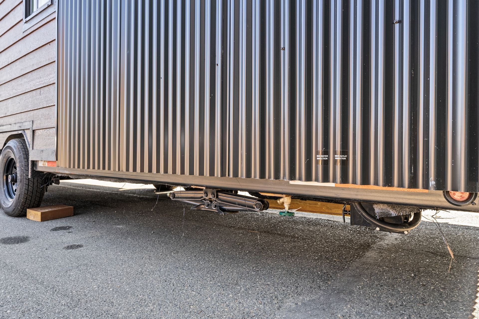 A tiny house on wheels is parked on the side of the road.