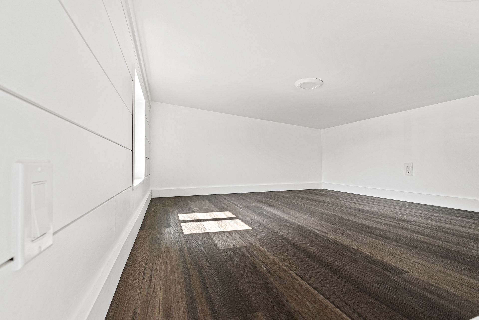 An empty room with hardwood floors and white walls.