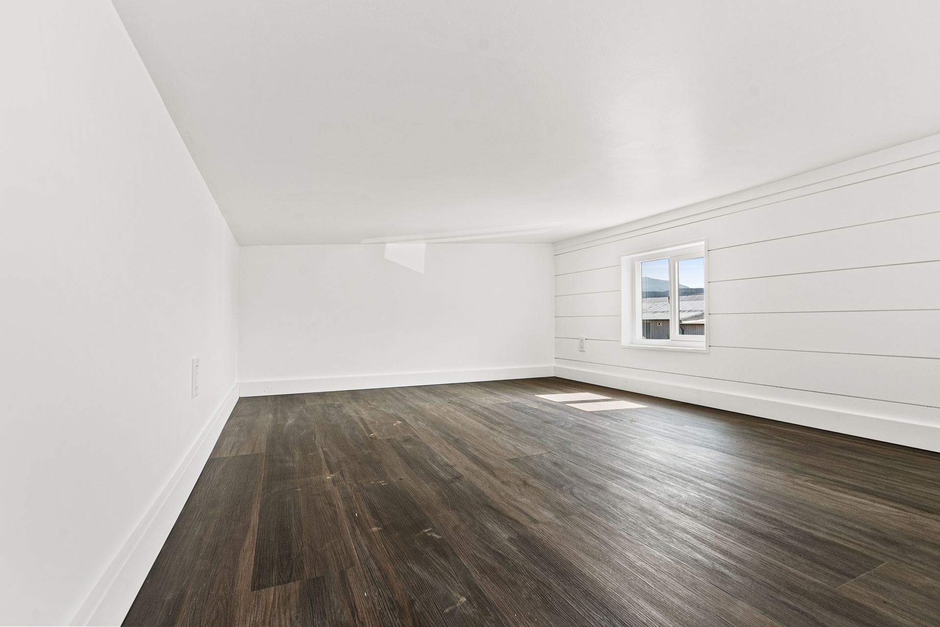 An empty room with hardwood floors and white walls